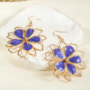 Detailed macro view of purple enamel flower earrings with golden metal petals and hooks