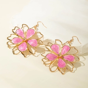 Detail of pink marble enamel flower earrings with golden alloy frames on white stone