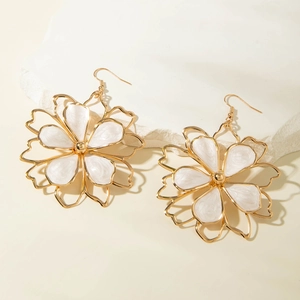 Detail view of gold flower earrings with white marble texture petals and hollow outlines