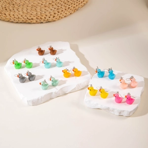 Macro shot of colorful resin duck earrings in ten vibrant shades on white stone props