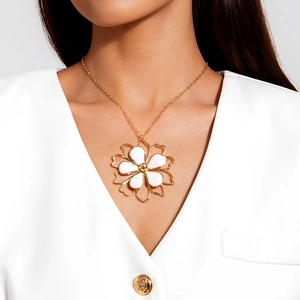 Detail of a large gold floral pendant necklace with white enamel petals on a model