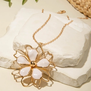 Detailed view of large white floral pendant necklace with gold trim on stone decor
