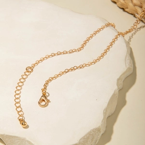 Detailed shot of golden fine link chain with lobster clasp and extension chain on white stone