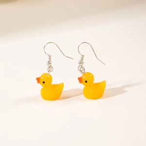 Detailed close-up of cute yellow resin duck earrings with silver hooks on white background