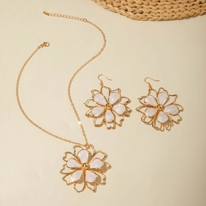 Detail of gold floral jewelry set featuring white enamel petals and layered metal edges