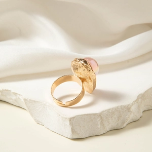 Detailopname van een gouden open ring met roze cabochon steen en gehamerde textuur