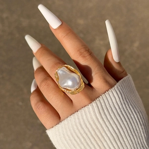 Detailopname van een barokparelring met gouden ringband op een stenen ondergrond