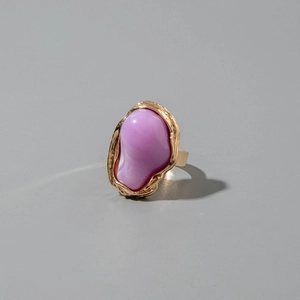 Gedetailleerde close-up van een vintage gouden ring met een getextureerde band en paarse steen