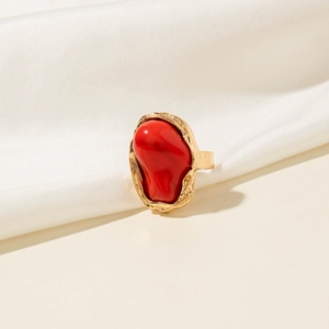 Detailopname van retro gouden ring met grote rode hars cabochon en unieke lava-achtige textuur