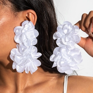 Detailed view of oversized white fabric flower earrings featuring a double-layered petal design
