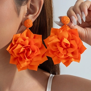 Detailed view of layered orange fabric flower earrings with textured satin petals
