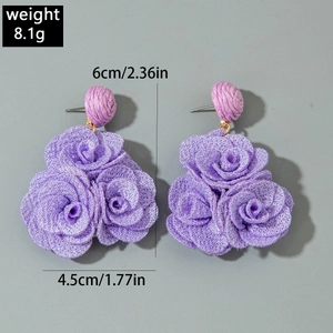 Detail view of purple fabric rose earrings with layered petals and matching woven bead hooks