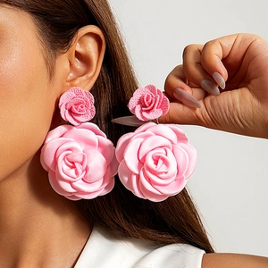 Close-up of a model wearing large pink fabric rose earrings with layered flower petals