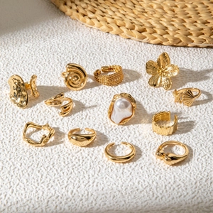 Flat lay of a 12-piece gold ring set featuring pearls, shells, and floral holiday designs