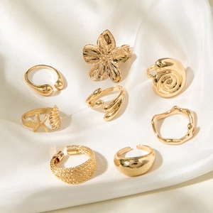 Close-up of gold alloy ring set with starfish, shell, and flower designs on silk