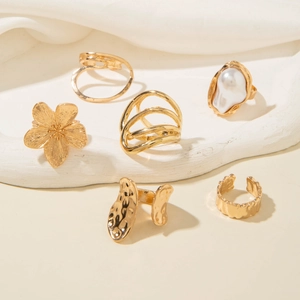 Detail shot of a 6-piece gold ring set featuring flower, pearl, and hammered textures