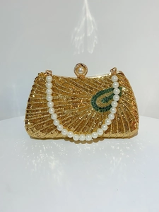 Detail of a vintage gold sequin evening clutch bag with pearl handle and green beaded accent