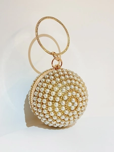 Macro shot of spherical evening bag featuring white pearls and a rhinestone ring handle