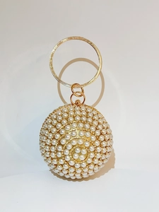 Detail of spherical pearl evening clutch with gold metal handle and crystal clasp