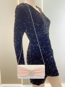 Pochette rose en strass avec boucle en cristal et chaîne argentée sur une robe noire