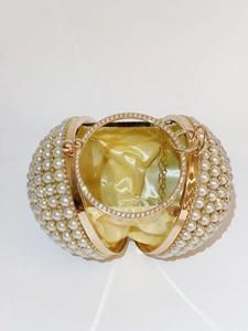 Macro view of spherical pearl evening bag with gold rhinestones ring handle and satin lining
