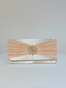 Détail d'une pochette de soirée en satin champagne avec design plissé et broche en cristal