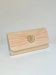 Détail de la pochette de soirée en satin champagne avec design plissé et broche en cristal