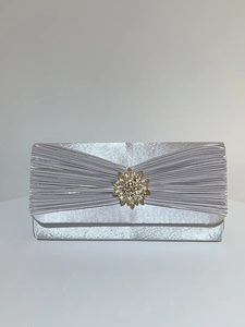Détail de la pochette de soirée argentée en satin plissé avec un motif soleil en strass brillants