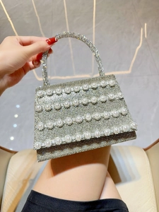 Close-up of silver rhinestone handbag featuring rows of white pearls and a crystal handle