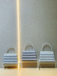 Elegant rhinestone evening handbags with pearl accents in silver and blue displayed on stands