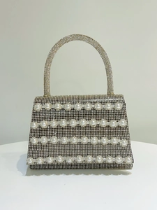 Detail of luxury rhinestone evening bag with elegant white pearl stripe embellishments