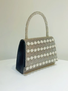 Detailed side view of silver rhinestone evening bag with elegant white pearl accents