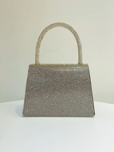 Close-up of a sparkling rhinestone evening clutch with an elegant arched pearl handle