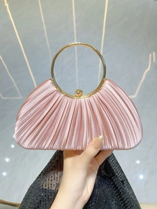 Close-up of pink pleated satin clutch featuring a round gold metal handle and snap closure