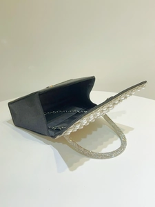 Detail of black evening clutch with pearl trim, rhinestone handle and metal chain strap