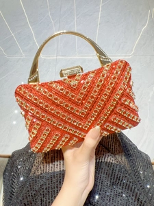 Dettaglio macro di strass rossi e oro a motivo V su borsa da sera di lusso chic