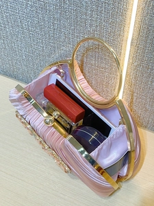 Detail view of pink satin evening clutch interior with smartphone and luxury essentials