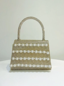 Detail of a luxury evening handbag with gold rhinestones and white pearl embellishments