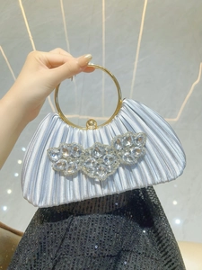 Detail of silver-blue pleated satin evening bag with rhinestone floral motif and gold ring