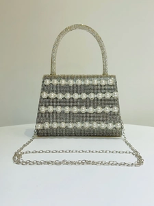 Macro detail of luxury evening bag with rows of white pearls and sparkling rhinestones