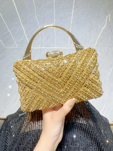 Dettaglio di una pochette da sera dorata con strass scintillanti e manico in metallo