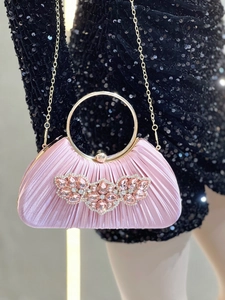 Close-up of pink pleated satin evening bag with crystal jewel brooch and gold handle