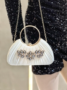 White pleated clutch bag with gold ring handle and dark grey gemstone embellishments