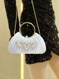 Detail of white pleated evening bag with gold ring handle and crystal rhinestone embellishment