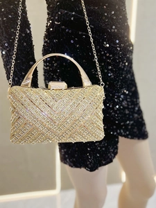 Pochette dorata con strass a V indossata su un abito nero con paillettes per occasioni
