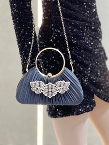 Detail of navy pleated evening clutch with crystal flower decor and gold ring handle