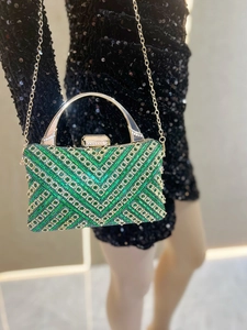 Dettaglio di paillettes smeraldo e trama geometrica a V sulla borsa da sera di lusso