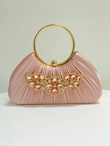 Detail of pink satin evening clutch with sparkling crystal flower and gold metal ring handle