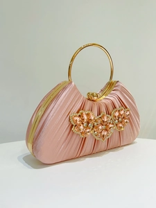 Detailed view of pink pleated satin evening bag with floral crystal rhinestones and gold ring handle