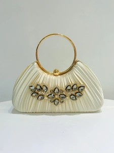Close-up of pleated beige satin evening tote bag with jewel embellishments and gold handle